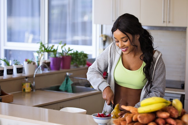 A person making a fresh fruit salad represents the balance of a healthy diet and regular exercise for maintaining good health and well-being